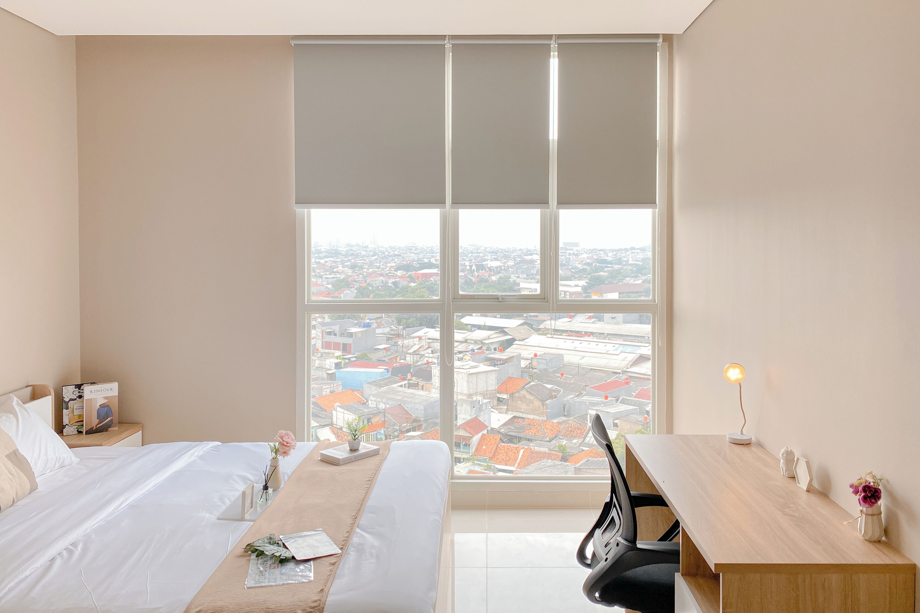 A hotel room with a large window, a bed, a desk, and a chair.