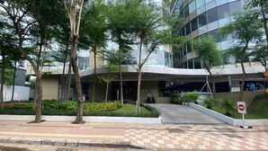 A modern building with a curved entrance, surrounded by trees and a checkered pavement. - Wonderful Thematic 2BR at Praxis Apartment (Surabaya)