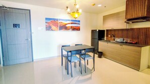 A compact kitchen with a dining area, a wooden cabinet, and a chandelier. - Wonderful Thematic 2BR at Praxis Apartment (Surabaya)