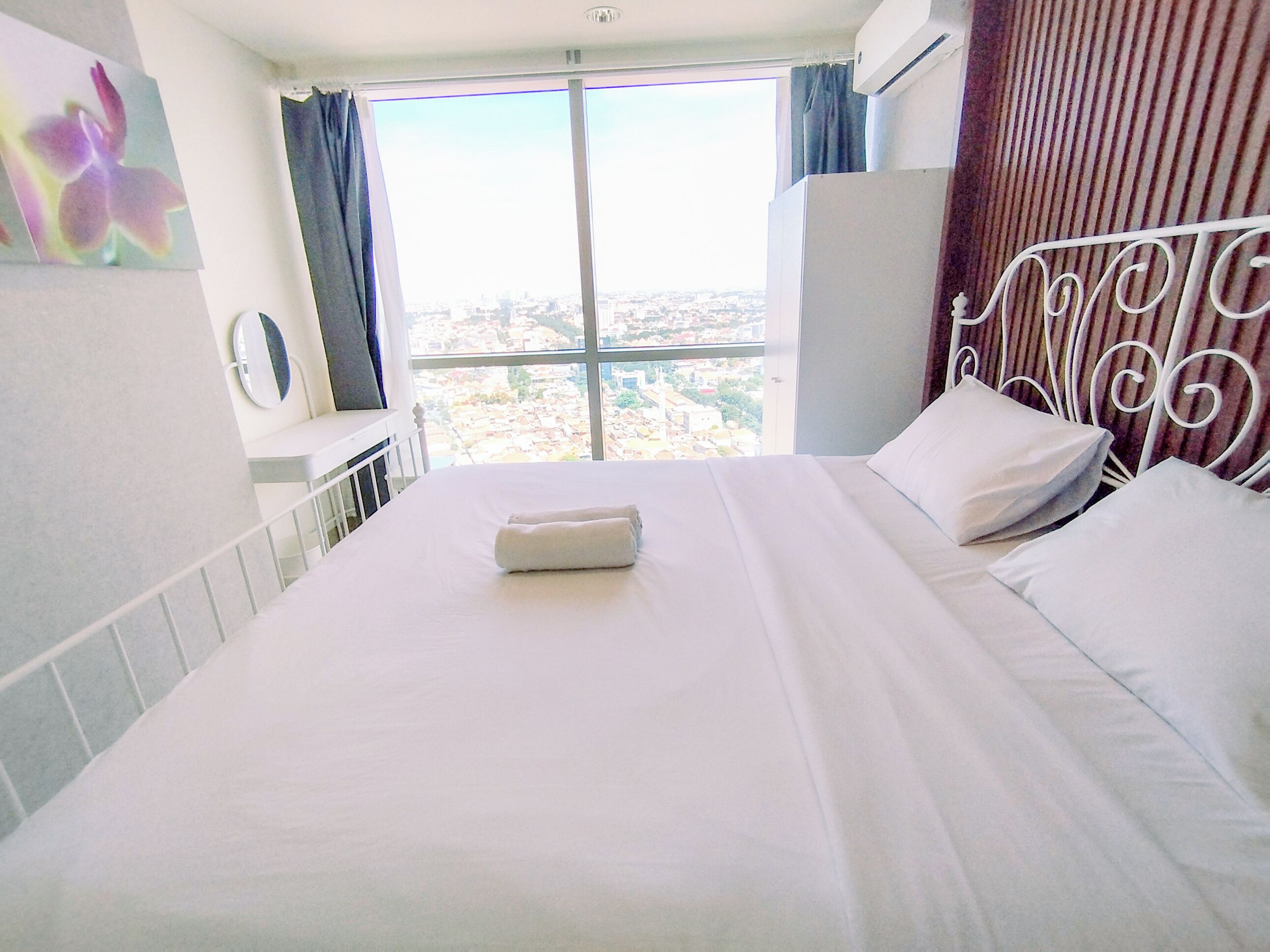 Ein Hotelzimmer mit Bett, einem Fenster mit Vorhängen und Blick auf die Stadt.
