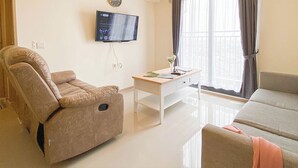 A living room with a sofa, a recliner, a coffee table, and a TV mounted on the wall.