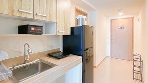 A modern kitchen with wooden cabinets, a stainless steel sink, and a black refrigerator.