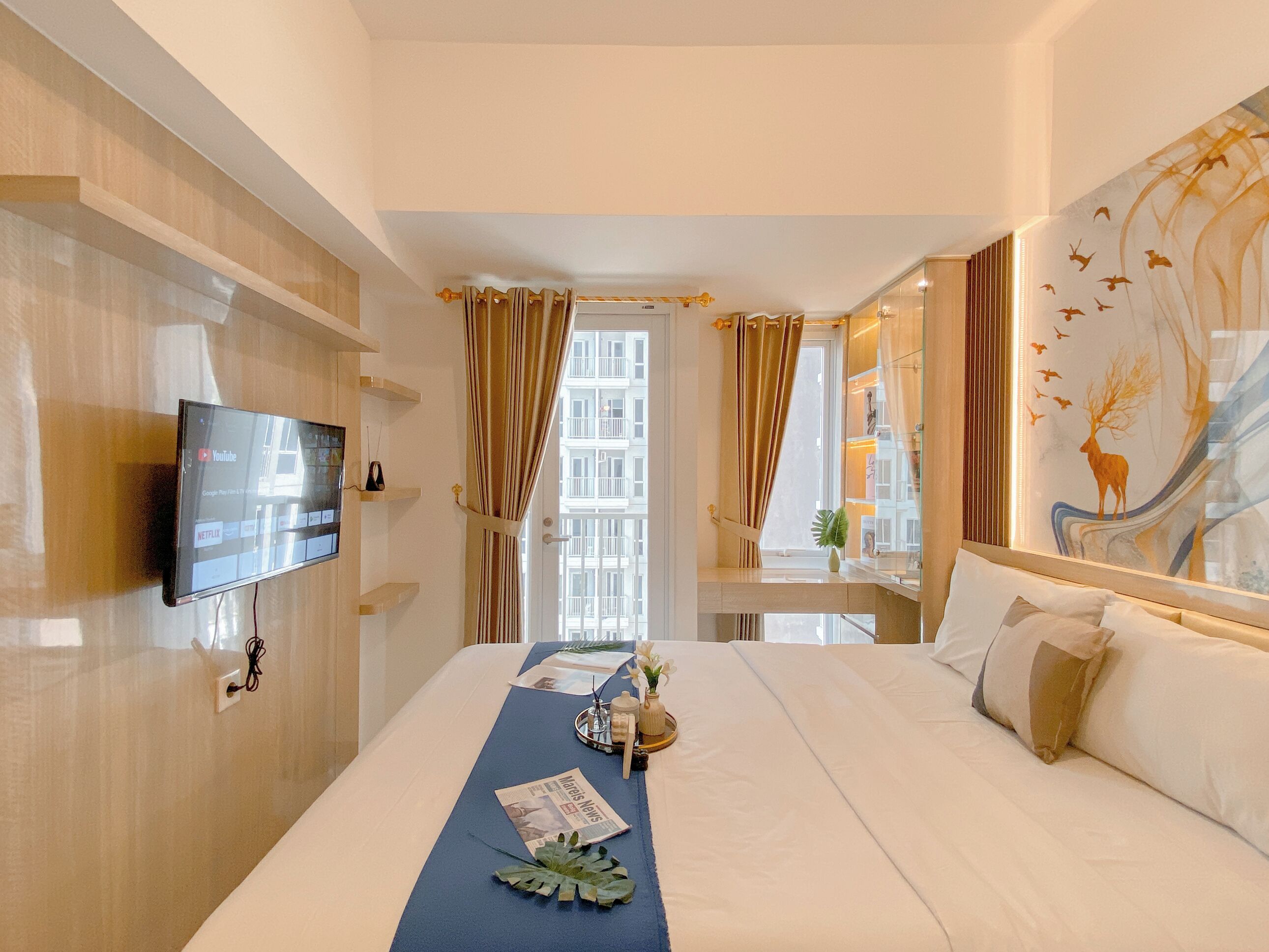 Ein Hotelzimmer mit Bett, Wandfernseher, Schreibtisch mit Stuhl und einem Vorhangfenster.