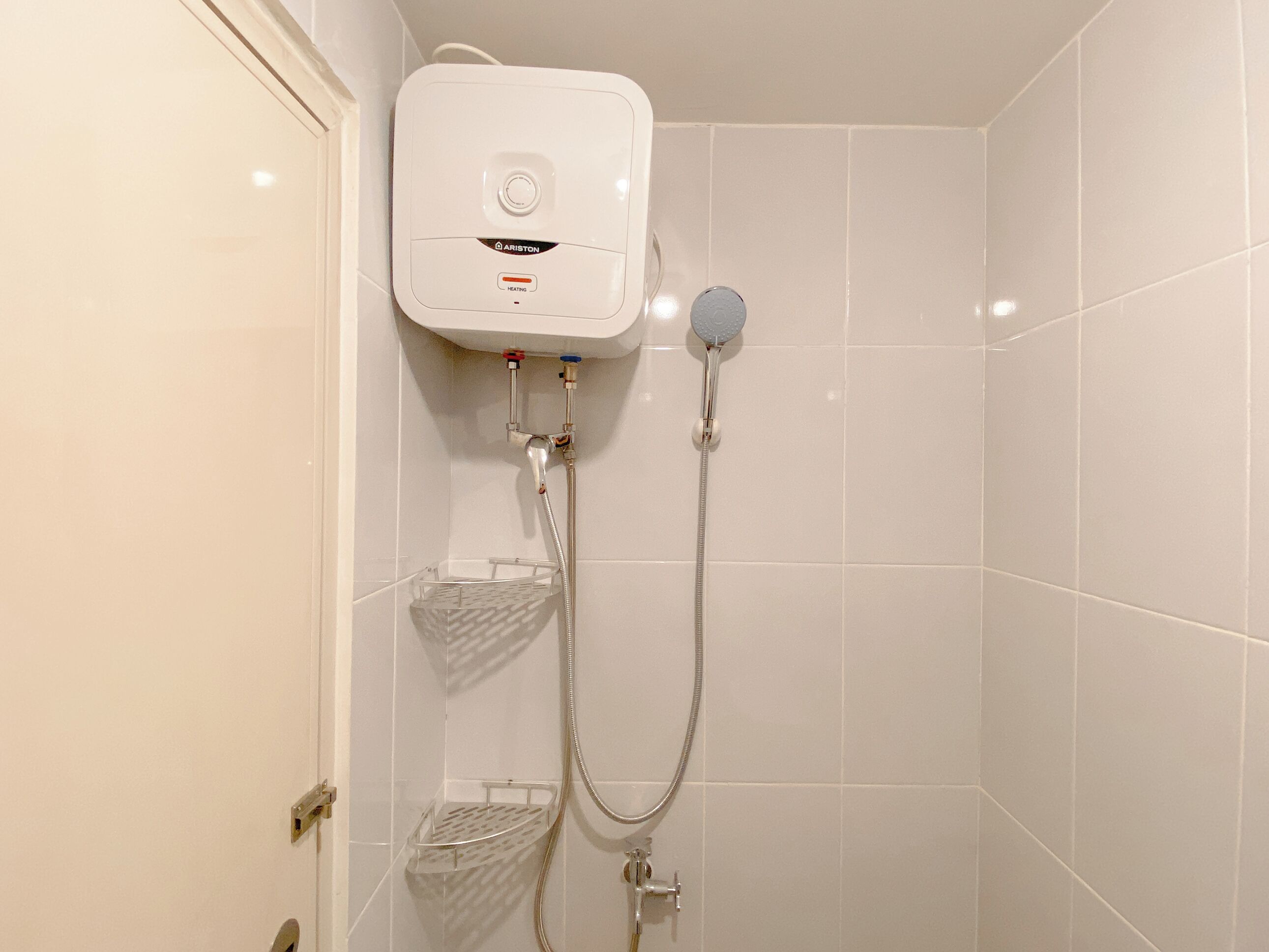 Ein Badezimmer mit einer weißen Duschkabine, einem Wandheizkörper und einer Handbrause.