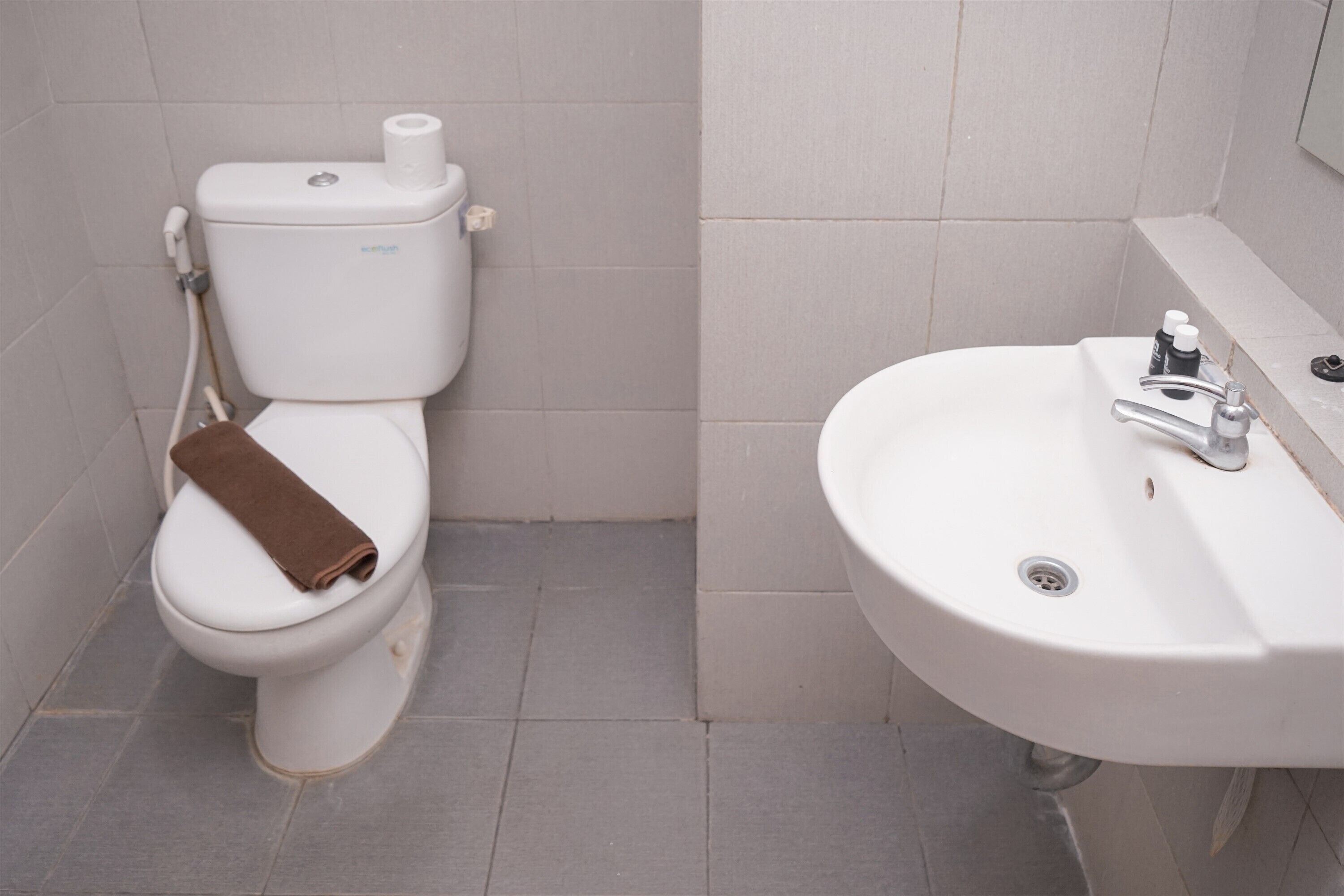Un baño con inodoro, lavamanos y piso de baldosas.