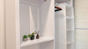 A bathroom with a white vanity, a mirror, a shelf with a potted plant and a bottle, and a white shower curtain. - Good Studio Room at Cinere Resort Apartment (Depok)