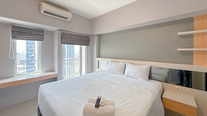 A hotel room with a large bed, a bedside table, a mirror, and a window with curtains. - Pleasant and Restful Studio at Orchard Supermall Mansion Apartment (Surabaya)
