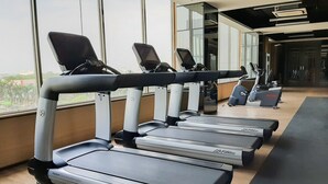 Varias caminadoras Life Fitness en un gimnasio con ventanas amplias y vistas a la ciudad.