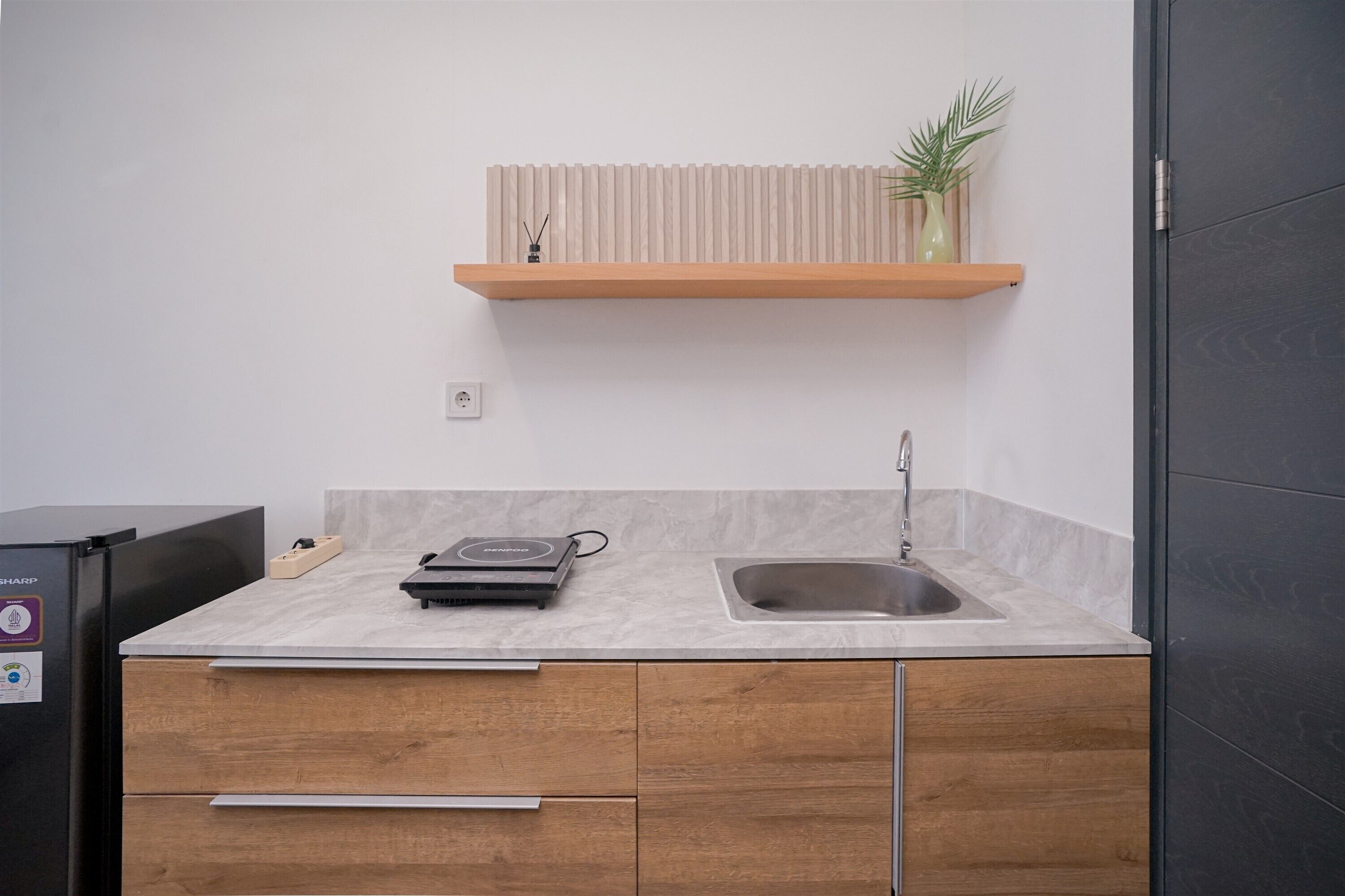 A compact kitchen with a countertop, a sink, and a wooden cabinet.