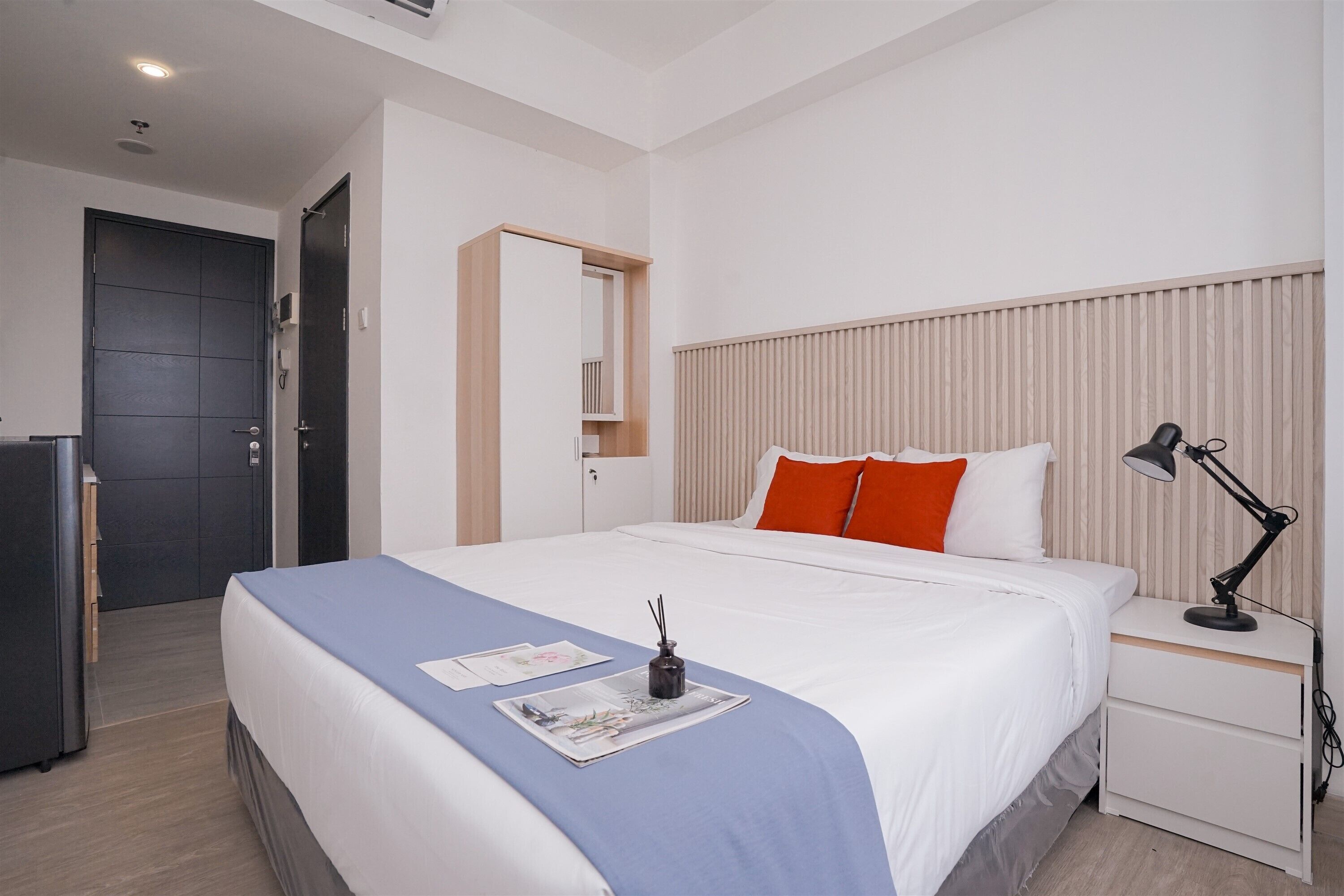 Et moderne hotelværelse med en stor seng, et natbord med en lampe og et klædeskab.