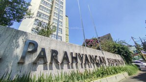 En skylt som visar Parahyangan-området, med en hög byggnad i bakgrunden.