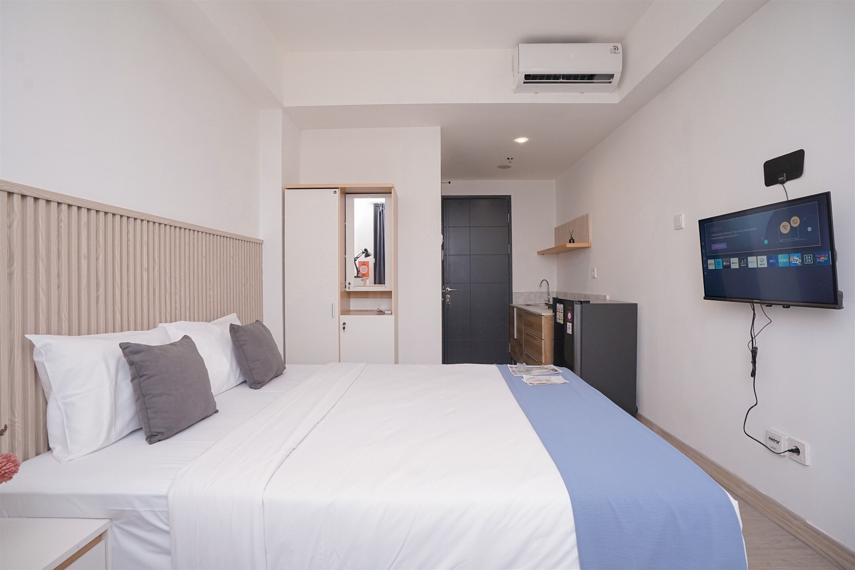 A hotel room with a bed, a TV, a desk, and a wardrobe.