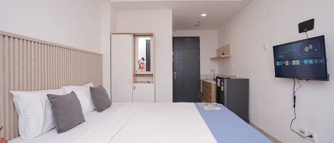 A hotel room with a bed, a TV, a desk, and a wardrobe.