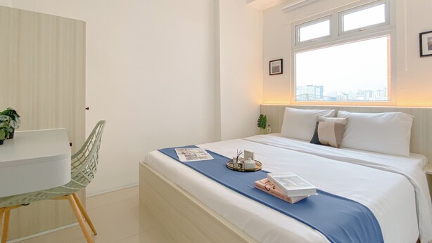 A modern bedroom with a bed, a desk, and a chair. - Good and Cozy 2BR at Green Pramuka City Apartment (Jakarta)