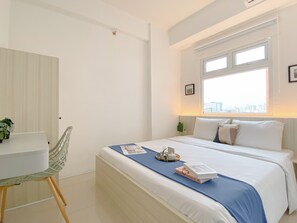 A modern bedroom with a bed, a desk, and a chair. - Good and Cozy 2BR at Green Pramuka City Apartment (Jakarta)
