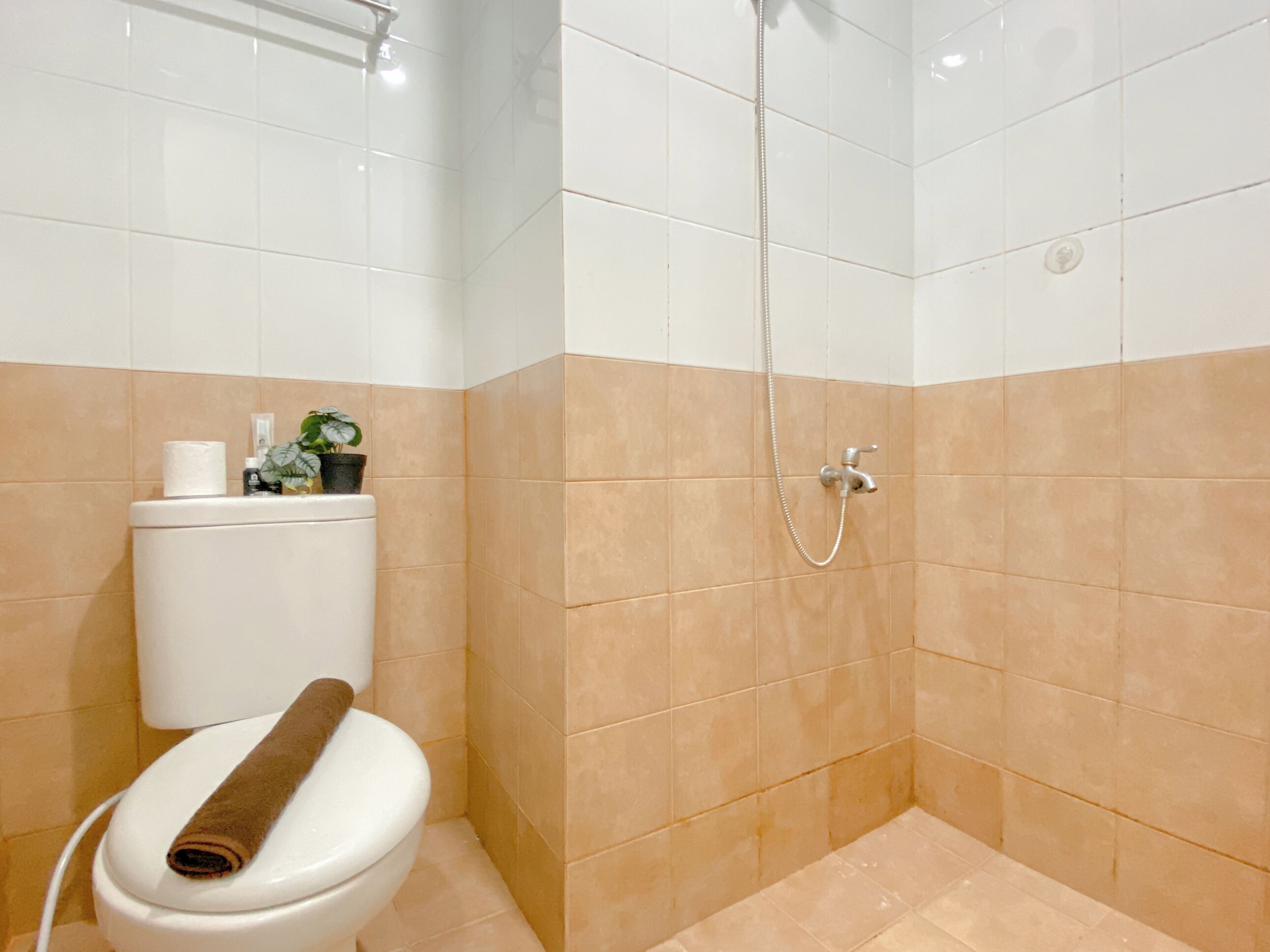 A bathroom with a toilet, a shower, and beige tiles.