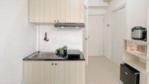 A compact kitchen with light wood cabinets, a stainless steel sink, and a built-in oven. - Good and Cozy 2BR at Green Pramuka City Apartment (Jakarta)