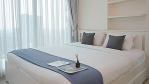 A neatly made bed with a blue blanket, a small decorative item, and a magazine on the bed. - Spacious 1BR at Tree Park City BSD Apartment (South Tangerang)