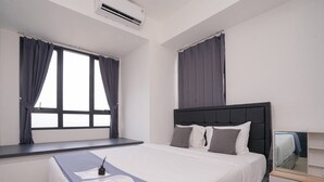 Un dormitorio con cama, mesita de noche, espejo y ventana con cortinas.