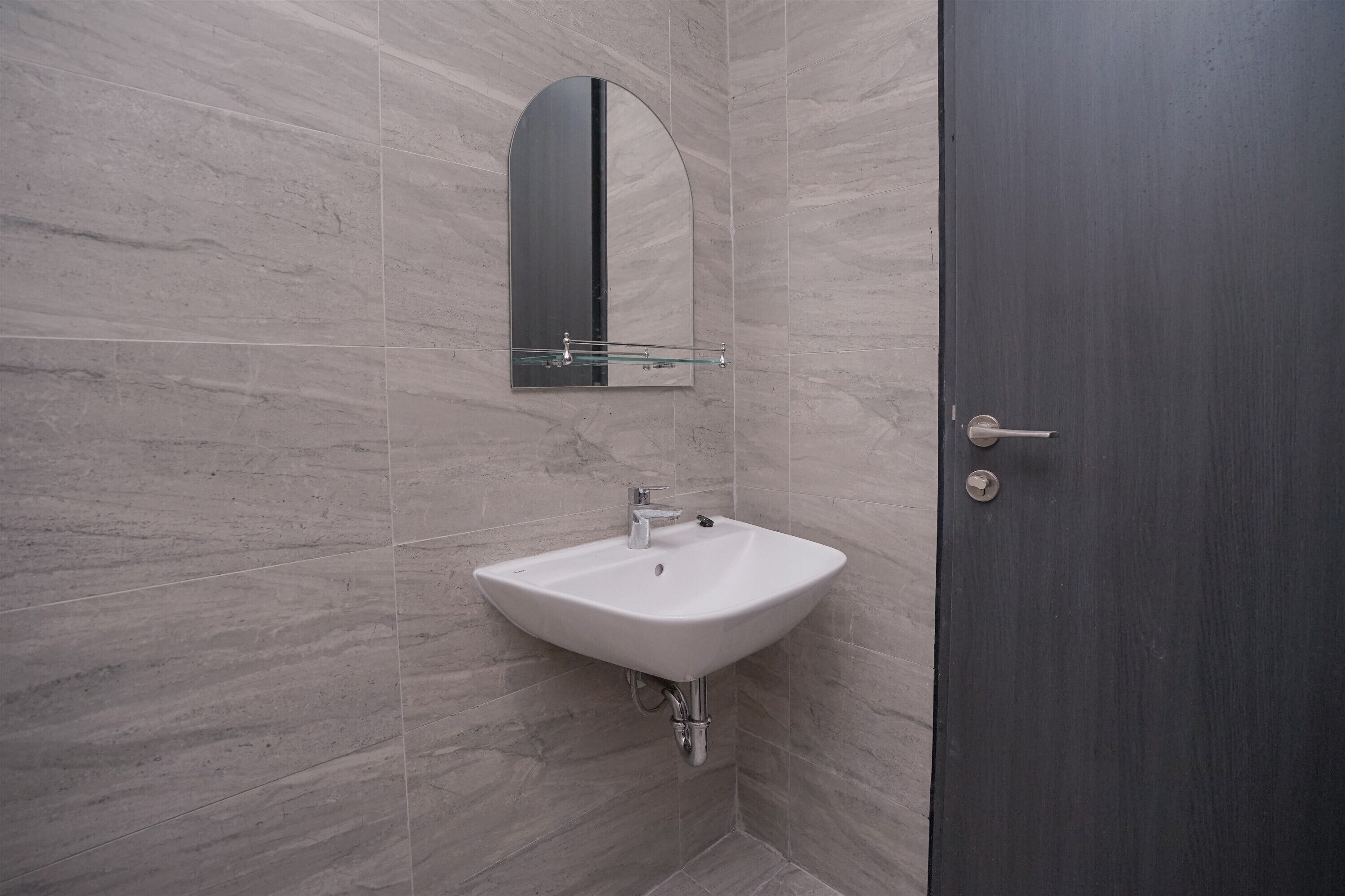 A bathroom with a white sink, a mirror, and a dark door.