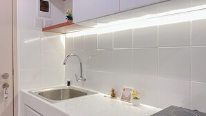 Une cuisine moderne avec des carreaux blancs, un évier en acier inoxydable et une plaque de cuisson à induction intégrée.