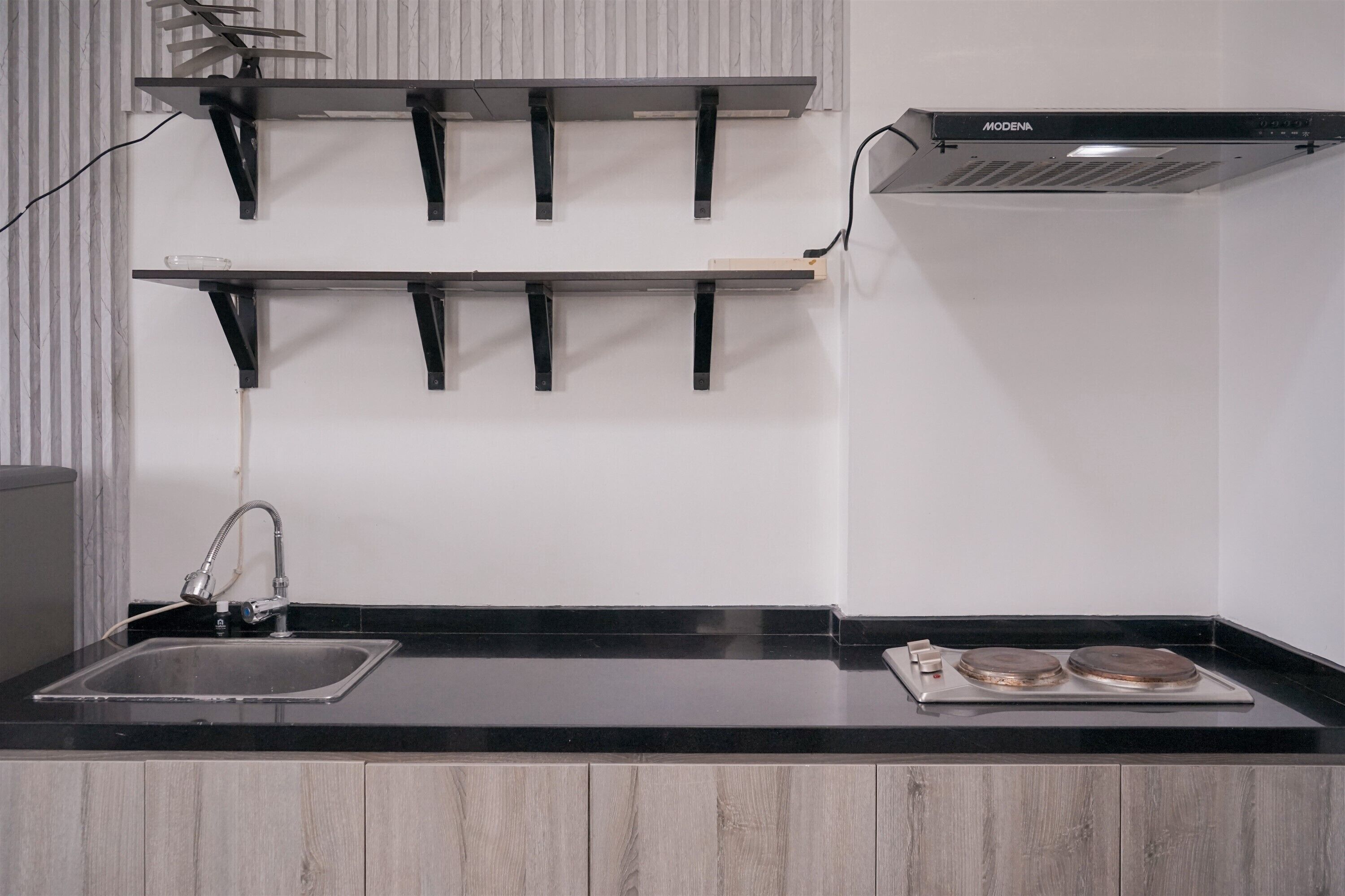 A kitchen with a black countertop, a stainless steel sink, and a double oven.