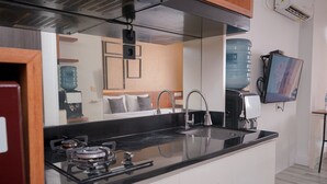 Una cocina moderna con encimera negra, electrodomésticos de acero inoxidable y un dispensador de agua grande.