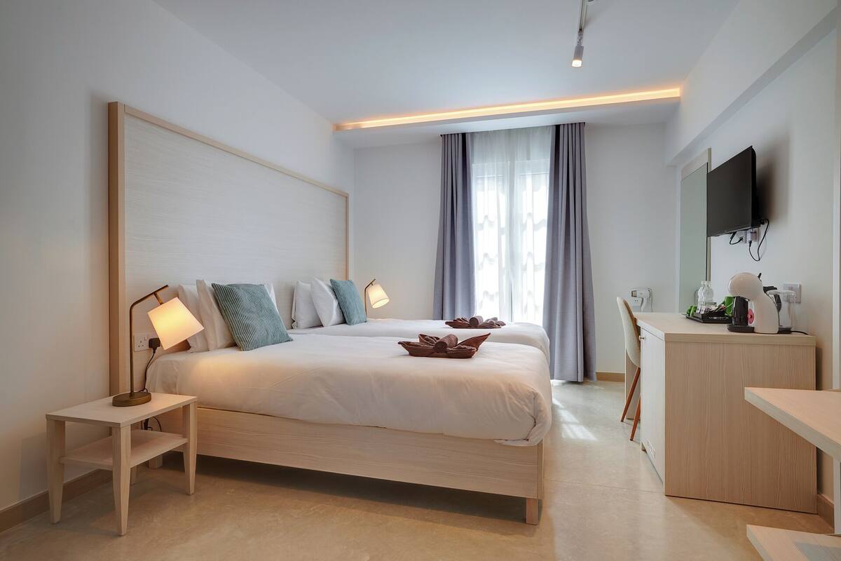 Een moderne hotelkamer met een groot bed, nachtkastjes, een bureau en een televisie.