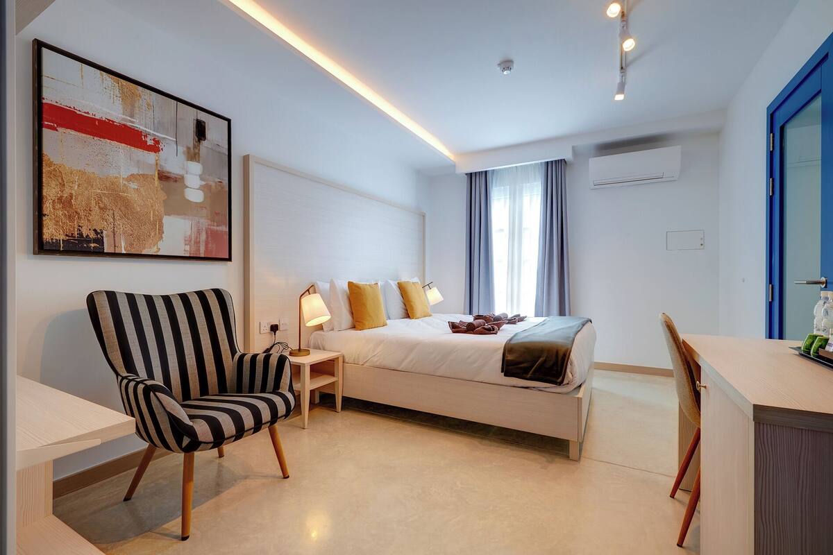 Een moderne hotelkamer met een bed, een bureau, een stoel en een schilderij aan de muur.