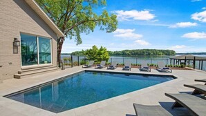 A rectangular swimming pool with lounge chairs and a view of a lake.