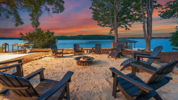 A lakeside deck with Adirondack chairs, a fire pit, and a gazebo overlooking the water.