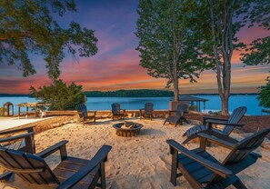 Une terrasse au bord du lac, agrémentée de chaises Adirondack, d’un foyer et d’un belvédère offrant une vue sur l’eau.