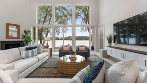 A spacious living room with a large window, a fireplace, and a flat-screen TV.