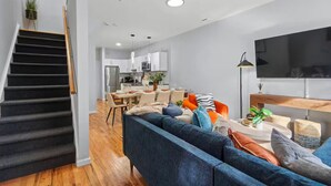 A modern living room with a sofa, coffee table, and TV. There is a staircase leading to another level.