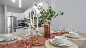 A dining table set with white plates, bowls, and glasses, surrounded by a pink cloth.