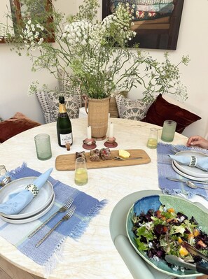 Een ronde eettafel met champagne, kaarsen en een bloemstuk van witte bloemen.