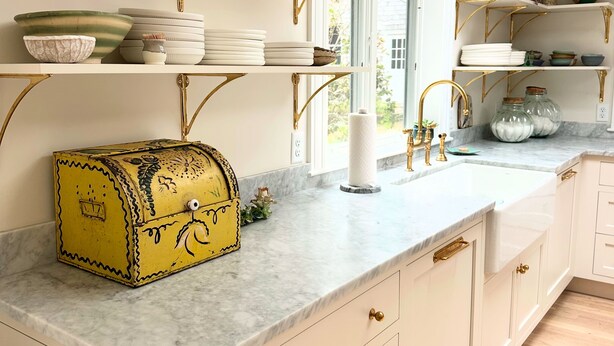 A kitchen with white cabinetry, gold fixtures, and a marble countertop. - 6bedroom, 4bath, chefs kitchen, central air, ping pong, walking distance to town (Tisbury)
