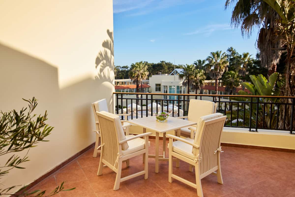 Ein Balkon mit Tisch und Stühlen, der auf einen Wohnbereich mit Palmen und Häusern blickt.