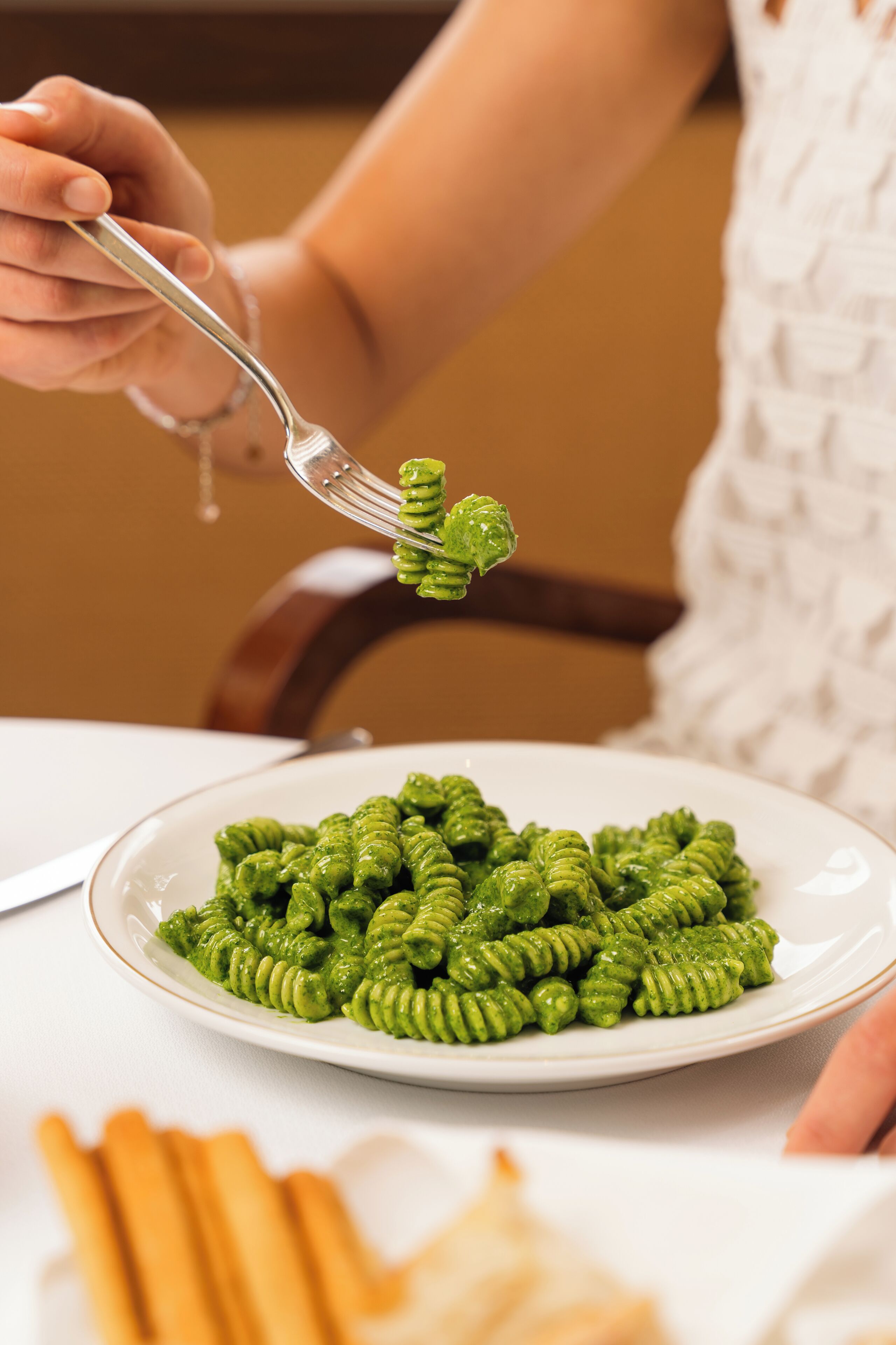 A plate of green pasta being served with a fork.