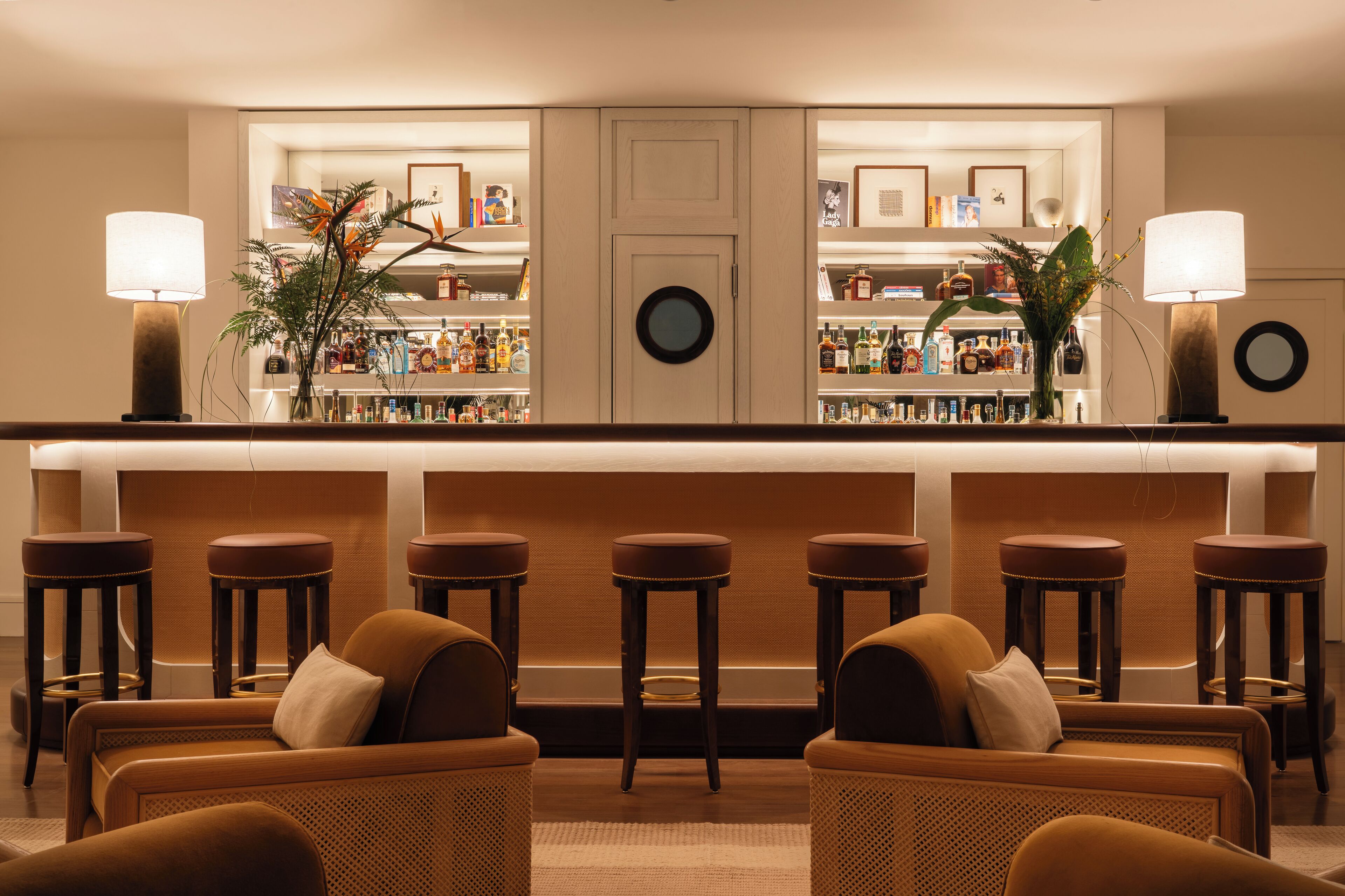 A bar area with stools, a counter, and a seating area with sofas.