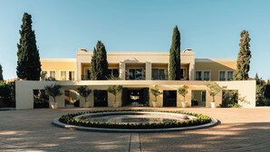 A modern building with a central courtyard, potted plants, and tall trees. - Locanda Punta del Este (Punta del Este)