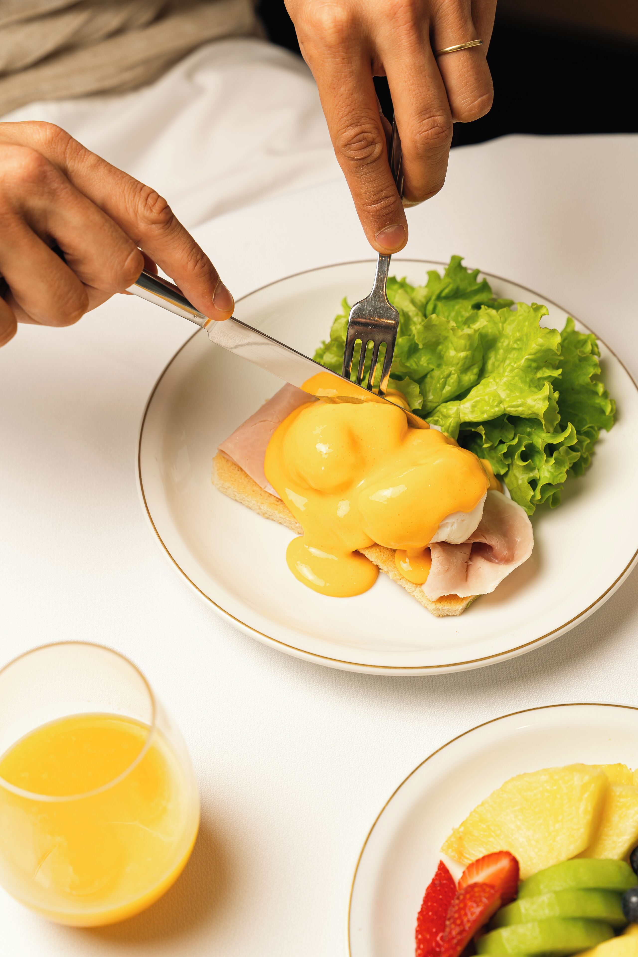 Ein Teller mit einem Sandwich, ein Glas Orangensaft und ein Obstteller.