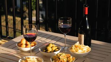 A table with plates of food and wine glasses on a balcony overlooking a scenic view.