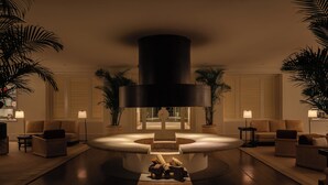 A modern living room with a central circular seating area, surrounded by sofas and lamps, with a large cylindrical structure above. - Locanda Punta del Este (Punta del Este)