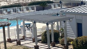 A pool area with a covered deck, lounge chairs, and a view of the ocean. - Plantation 2215 (Gulf Shores)