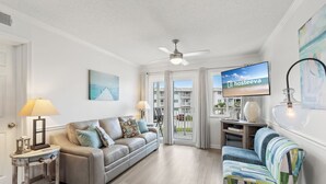 A living room with a sofa, armchairs, a TV, and a ceiling fan. - Plantation 2215 (Gulf Shores)