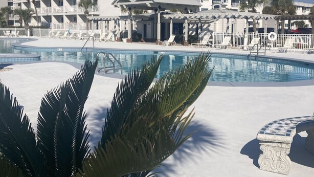 A hotel with a pool area, including lounge chairs and palm trees. - Plantation 2215 (Gulf Shores)