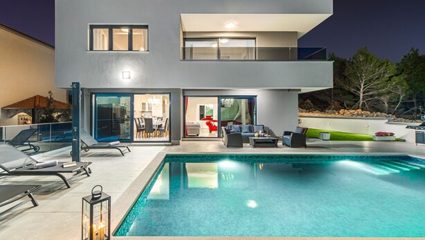 A modern two-story house with a swimming pool, outdoor seating, and a dining area visible through the glass doors. - Villa Shaula (Sibenik)