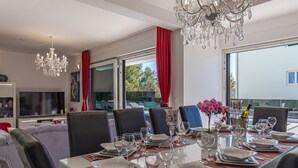 A dining area with a glass table, chairs, and a chandelier. - Villa Shaula (Sibenik)