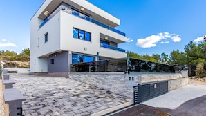 A modern two-story house with a stone facade, large windows, and a covered outdoor area. - Villa Shaula (Sibenik)